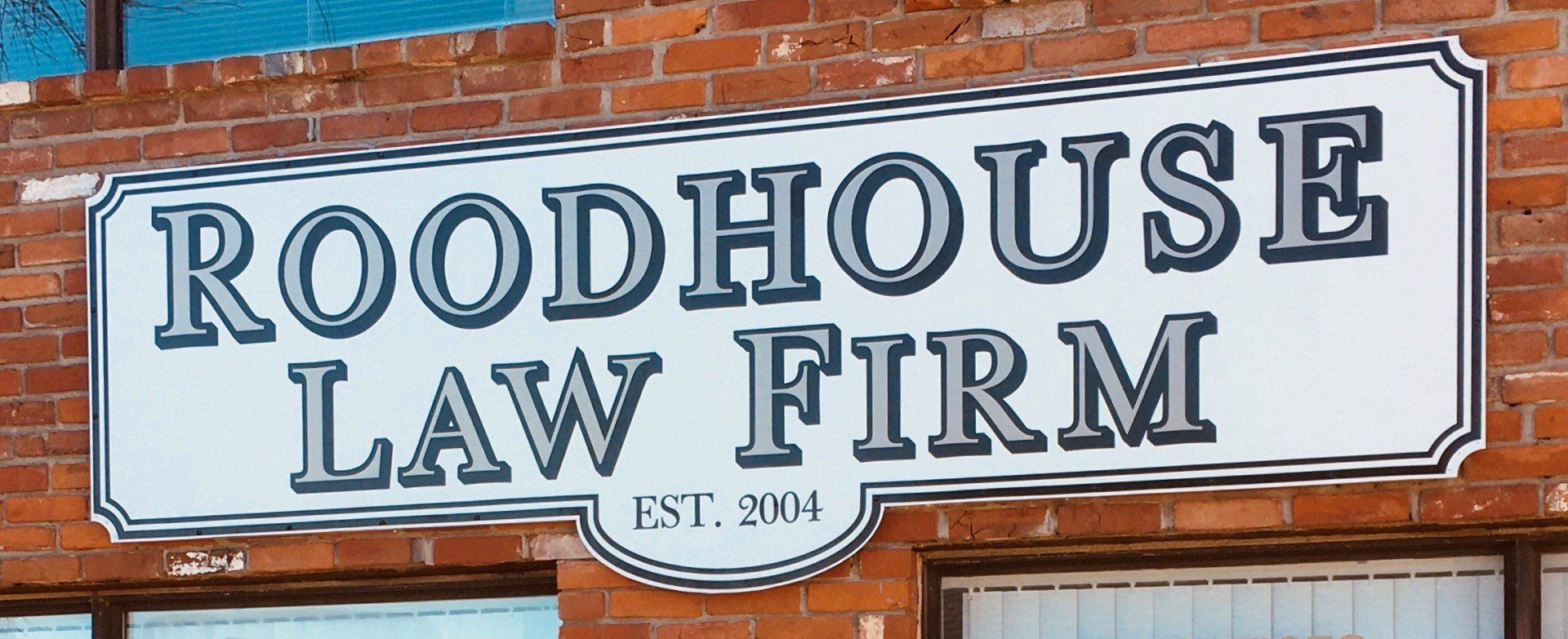 A sign for roodhouse law firm is on a brick building
