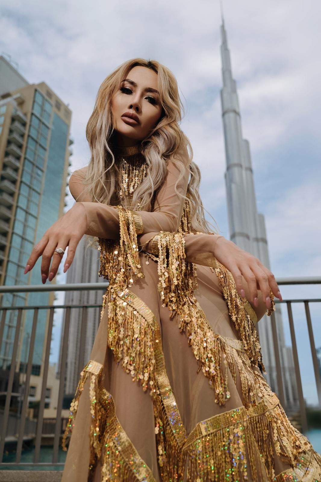 Woman in gold dress poses in front of Burj Khalifa, Dubai.
