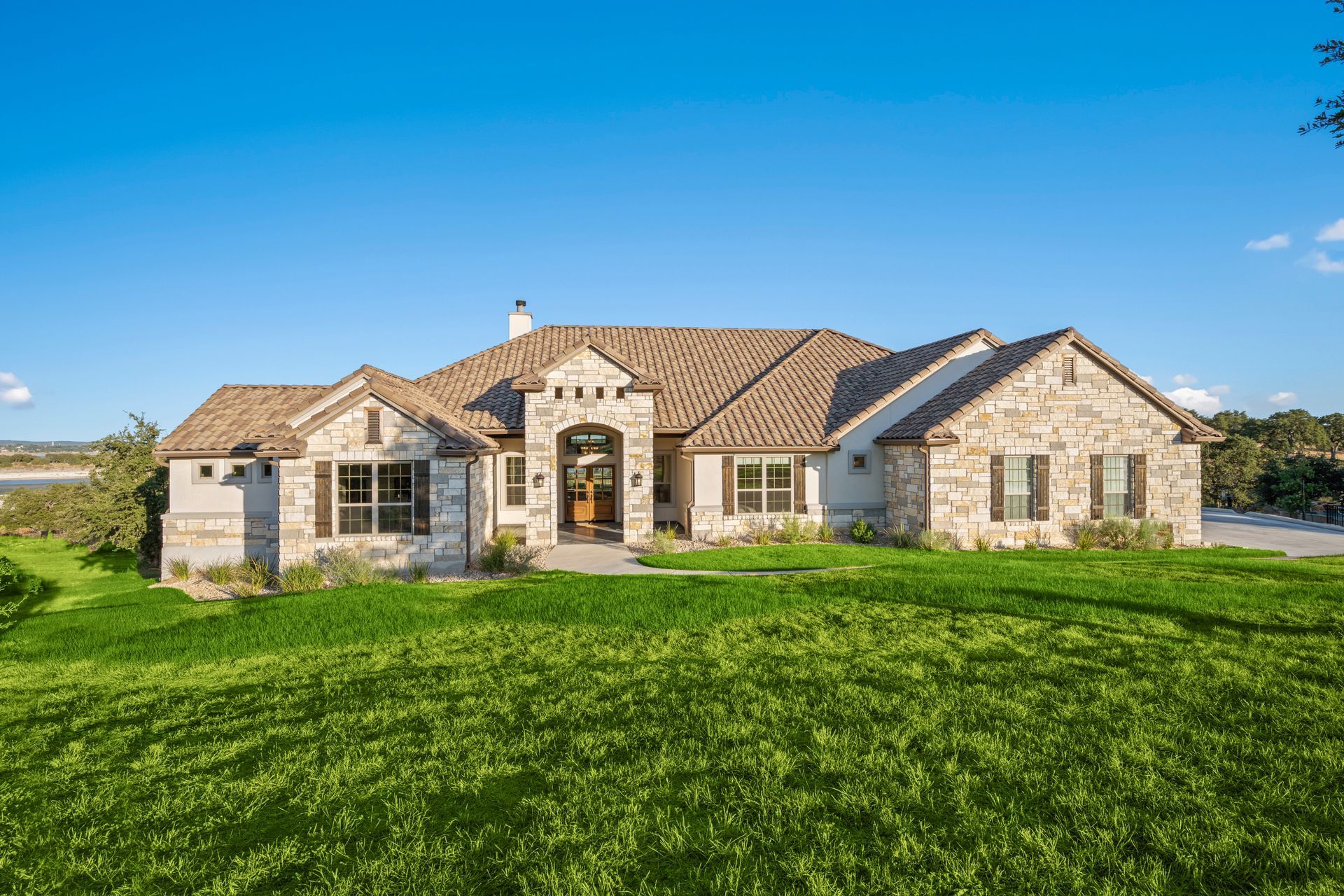 A large house is sitting on top of a lush green field.