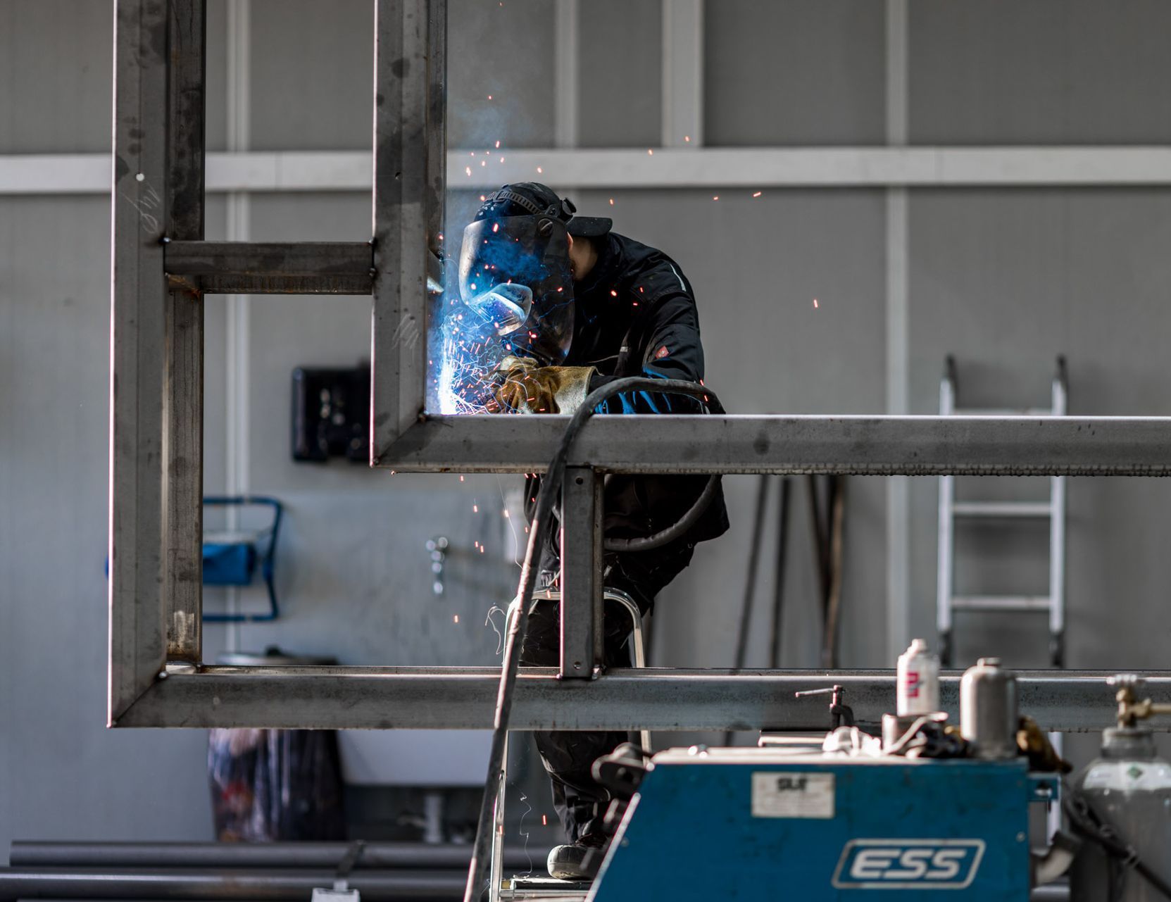 Ein Mann schweißt in einer Fabrik eine Metallstruktur.