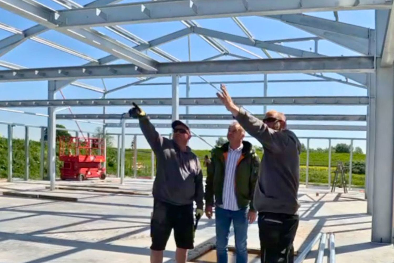 Three men are standing in a building under construction.