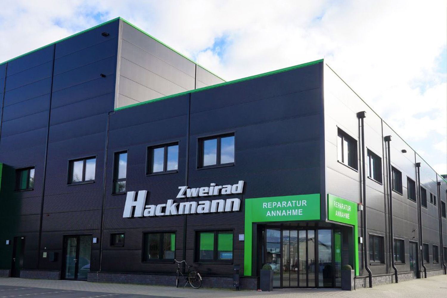 A large black building with a green entrance and a sign that says zweirad hackmann.