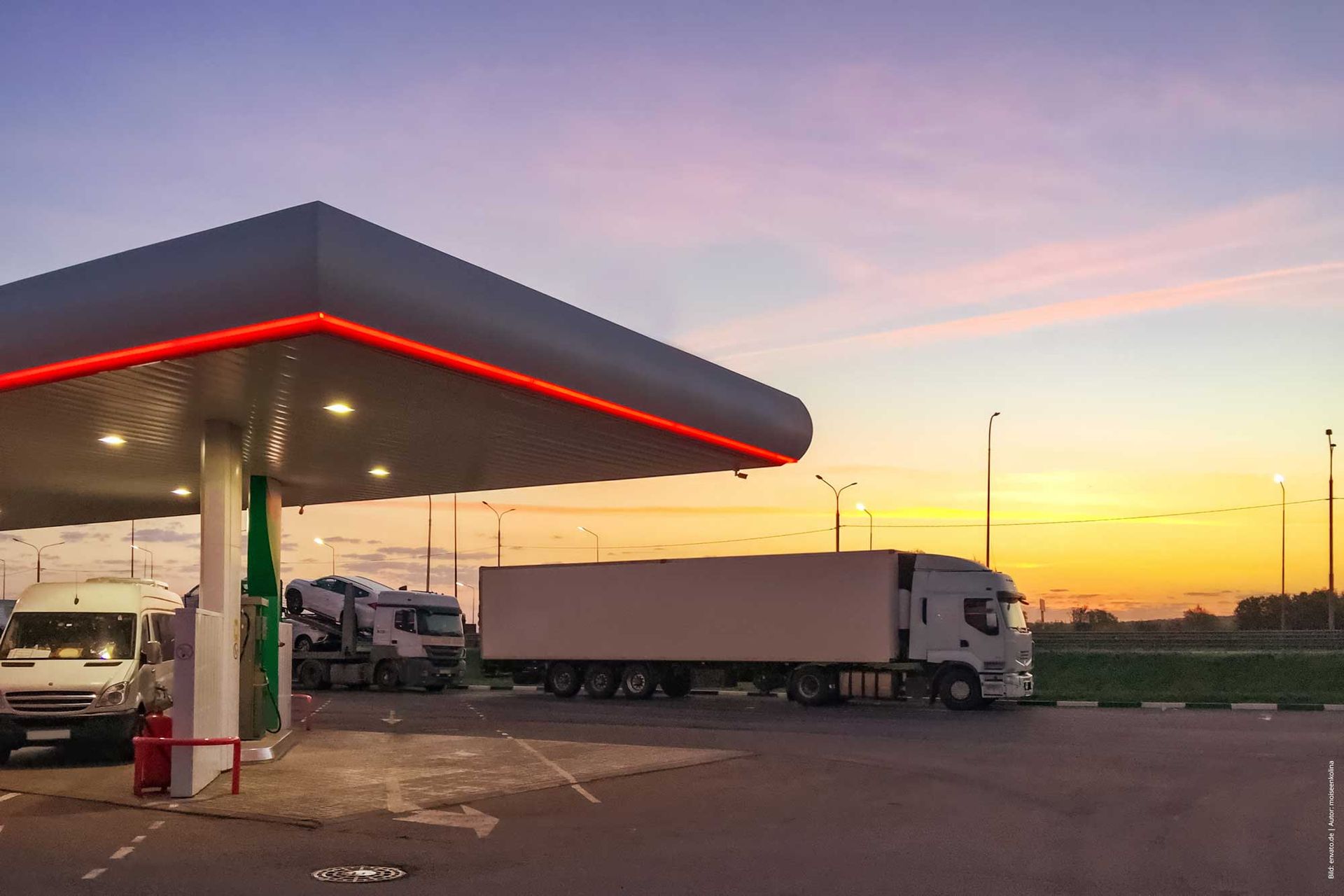 Eine Tankstelle mit davor geparkten Lastwagen bei Sonnenuntergang.