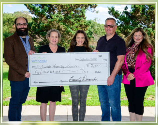 Five people hold a large check for $5,000 made out to 