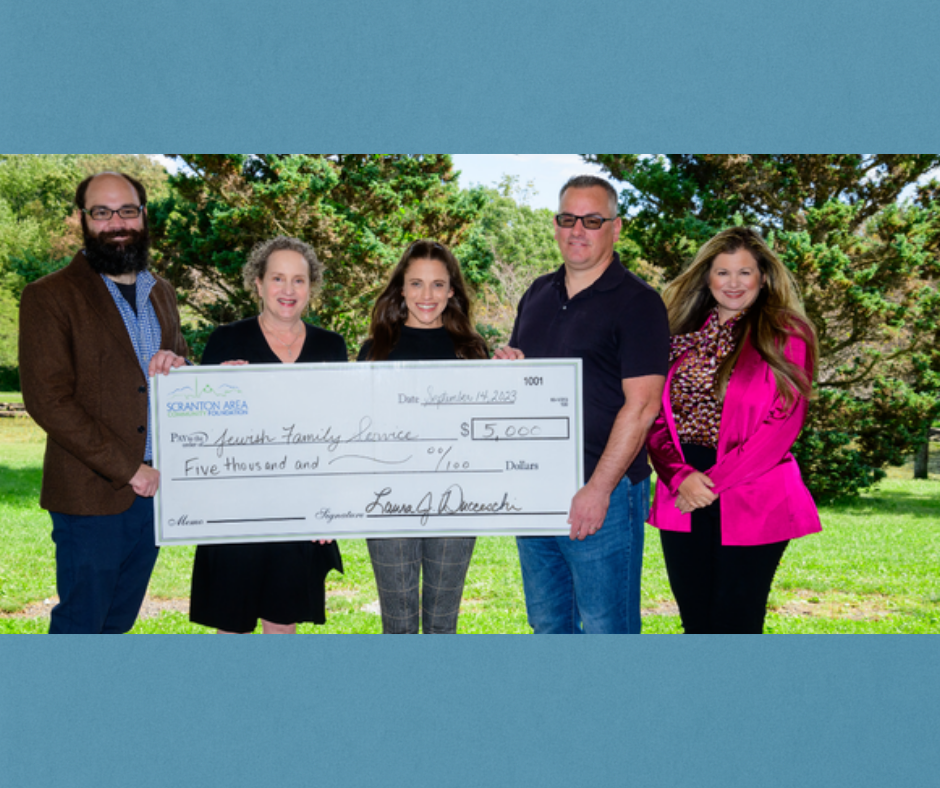 Five people hold a large check for $5,000 made out to 