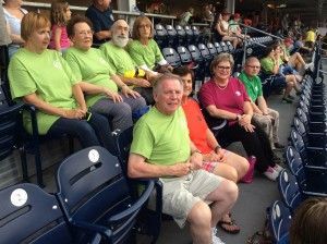 A group of people wearing green shirts sit in stadium seats, watching an event.