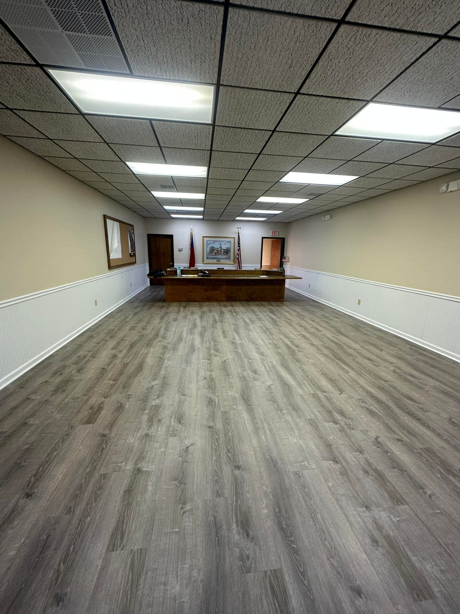 A large room with a wooden floor and a table in the middle.