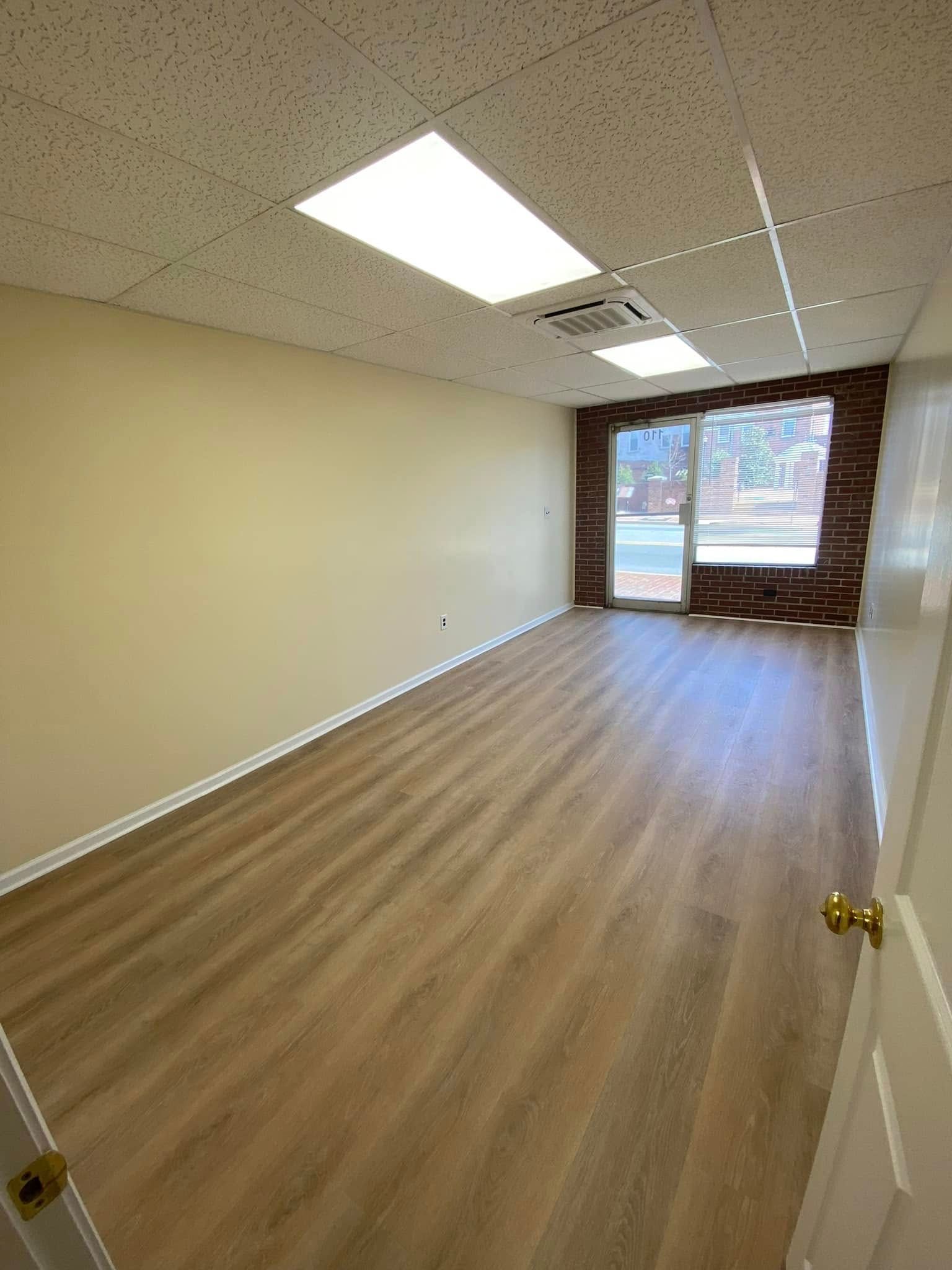 An empty room with hardwood floors and a brick wall.