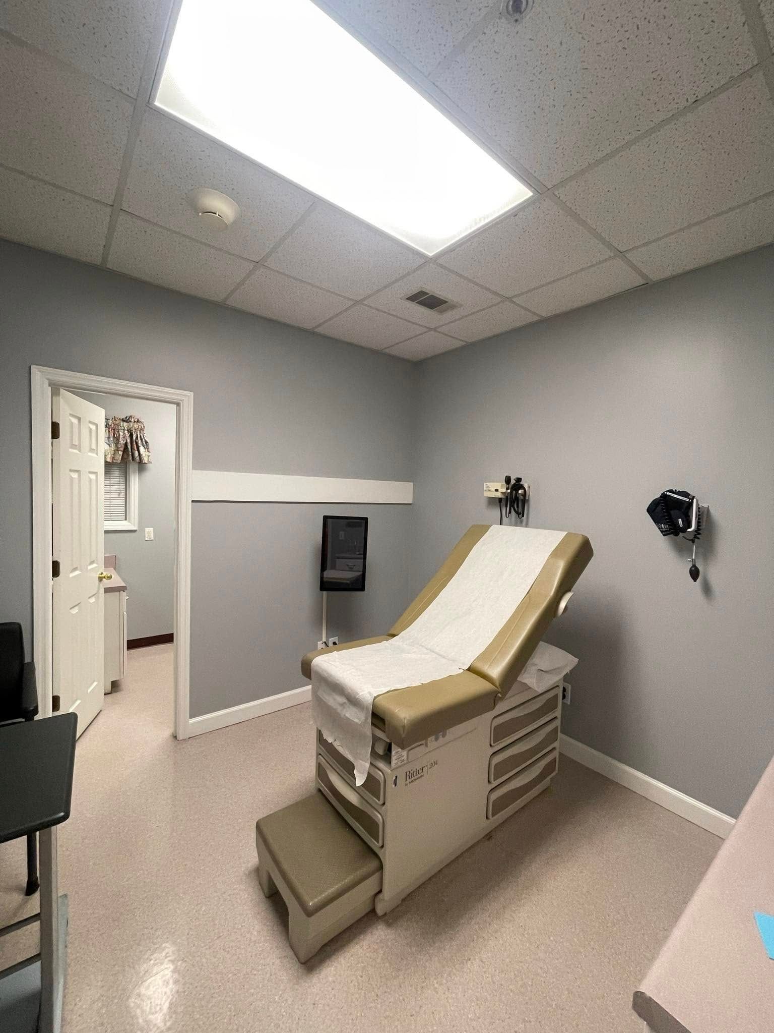 A doctor 's office with a examination table in the middle of the room.