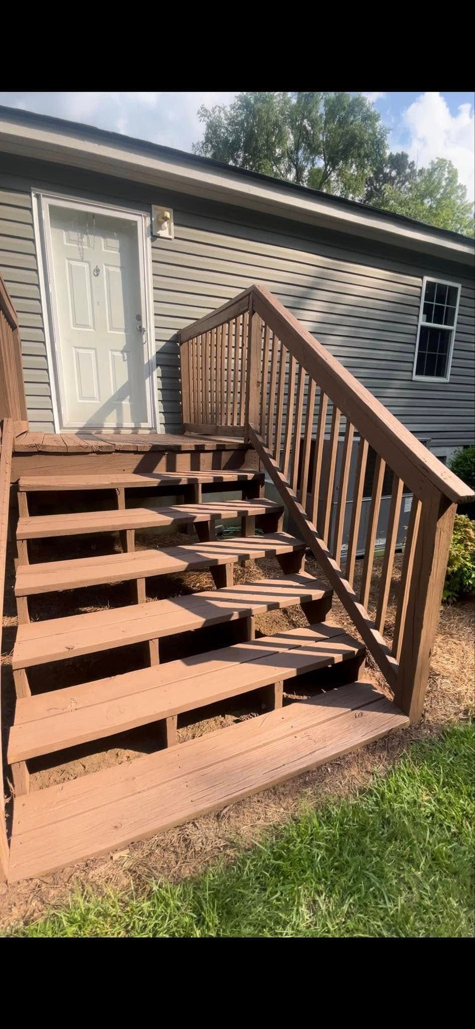 A wooden deck with stairs leading up to a house.