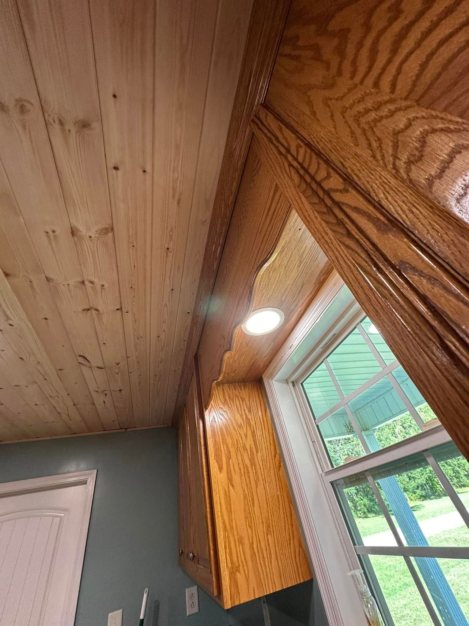 A kitchen with wooden cabinets and a large window.