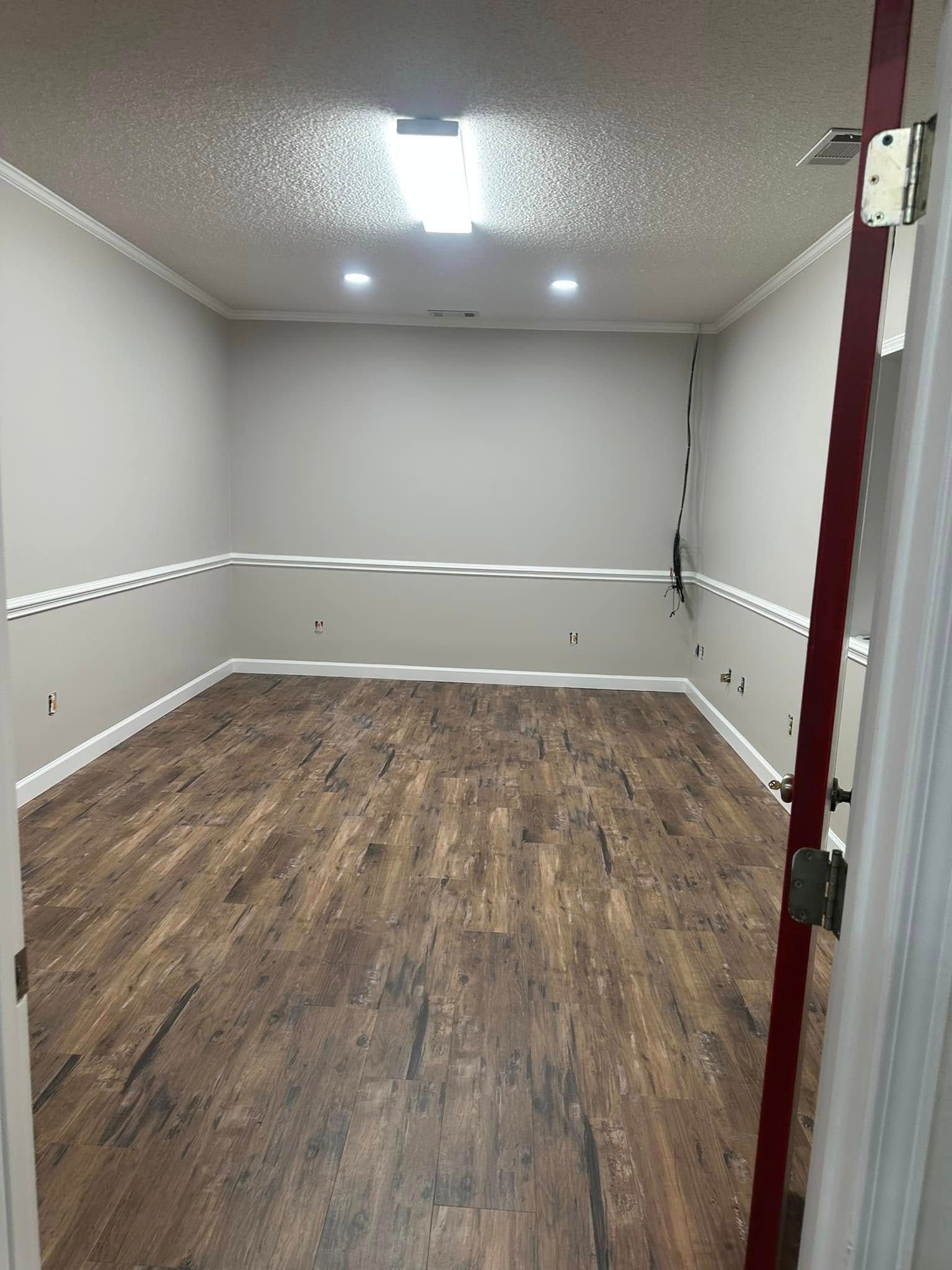A large empty room with hardwood floors and white trim.