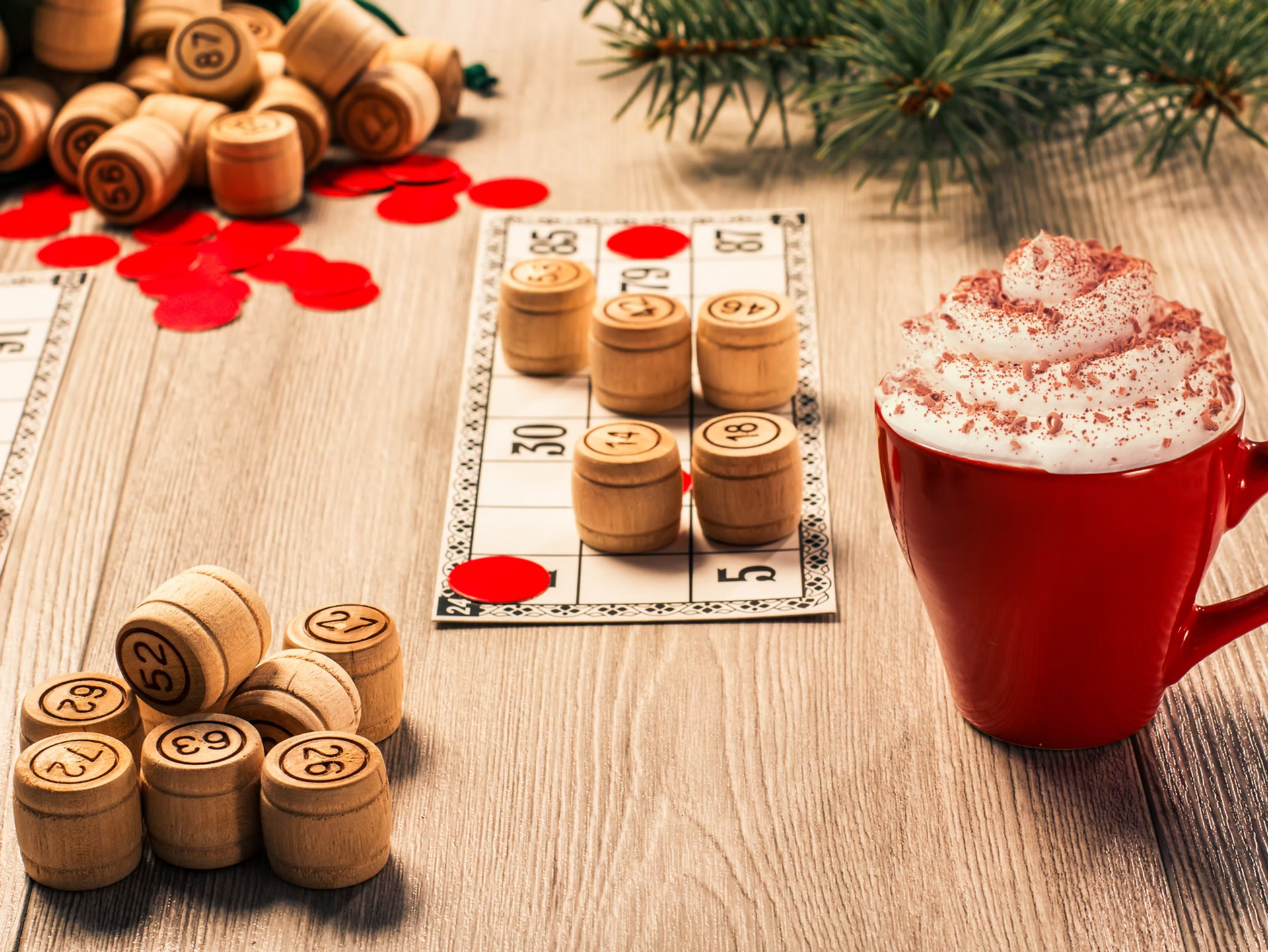 Wooden corks arranged on a game board beside red paint splatters and a whipped cream drink on a table
