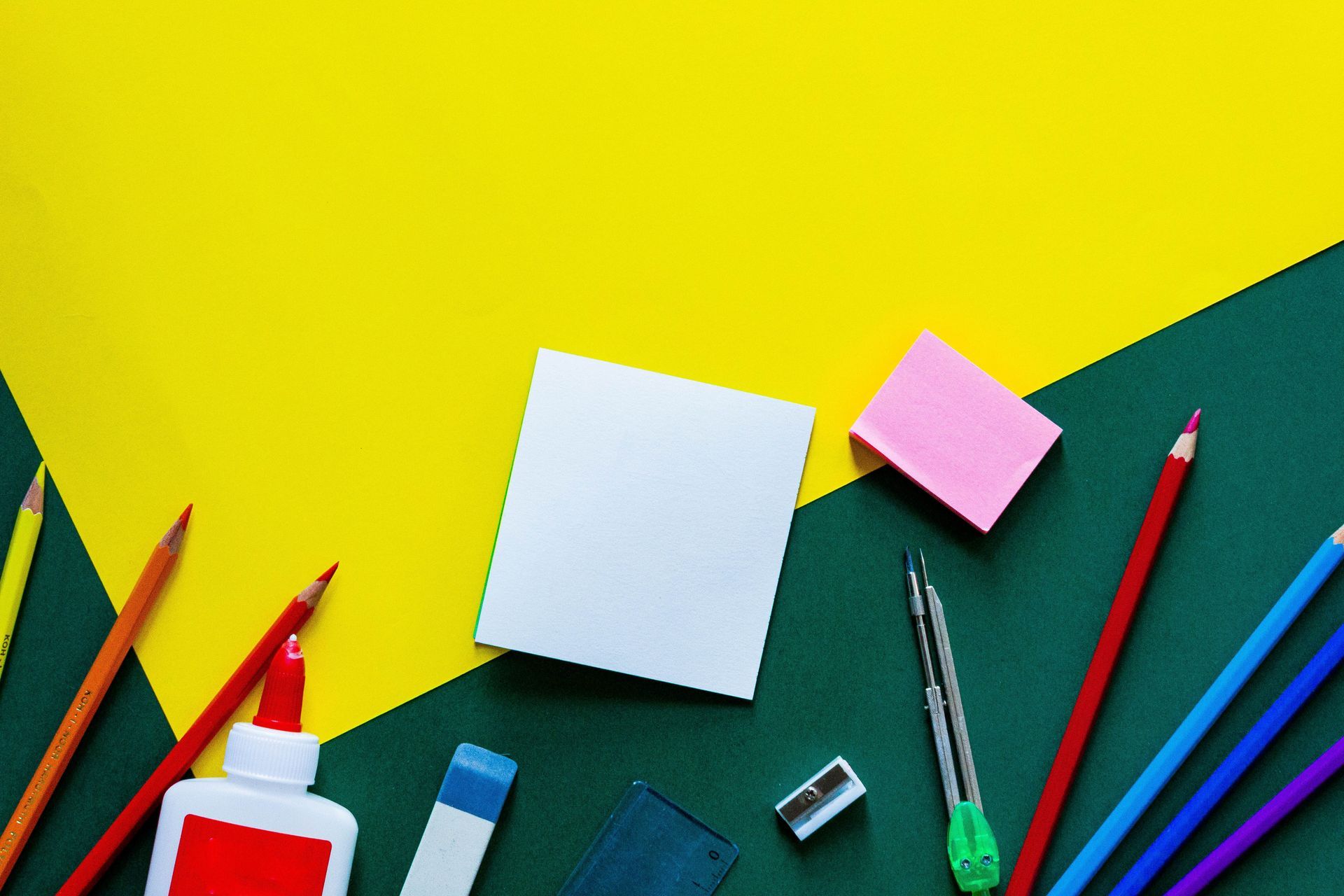 Art supplies around blank note cards on a yellow and green desk background