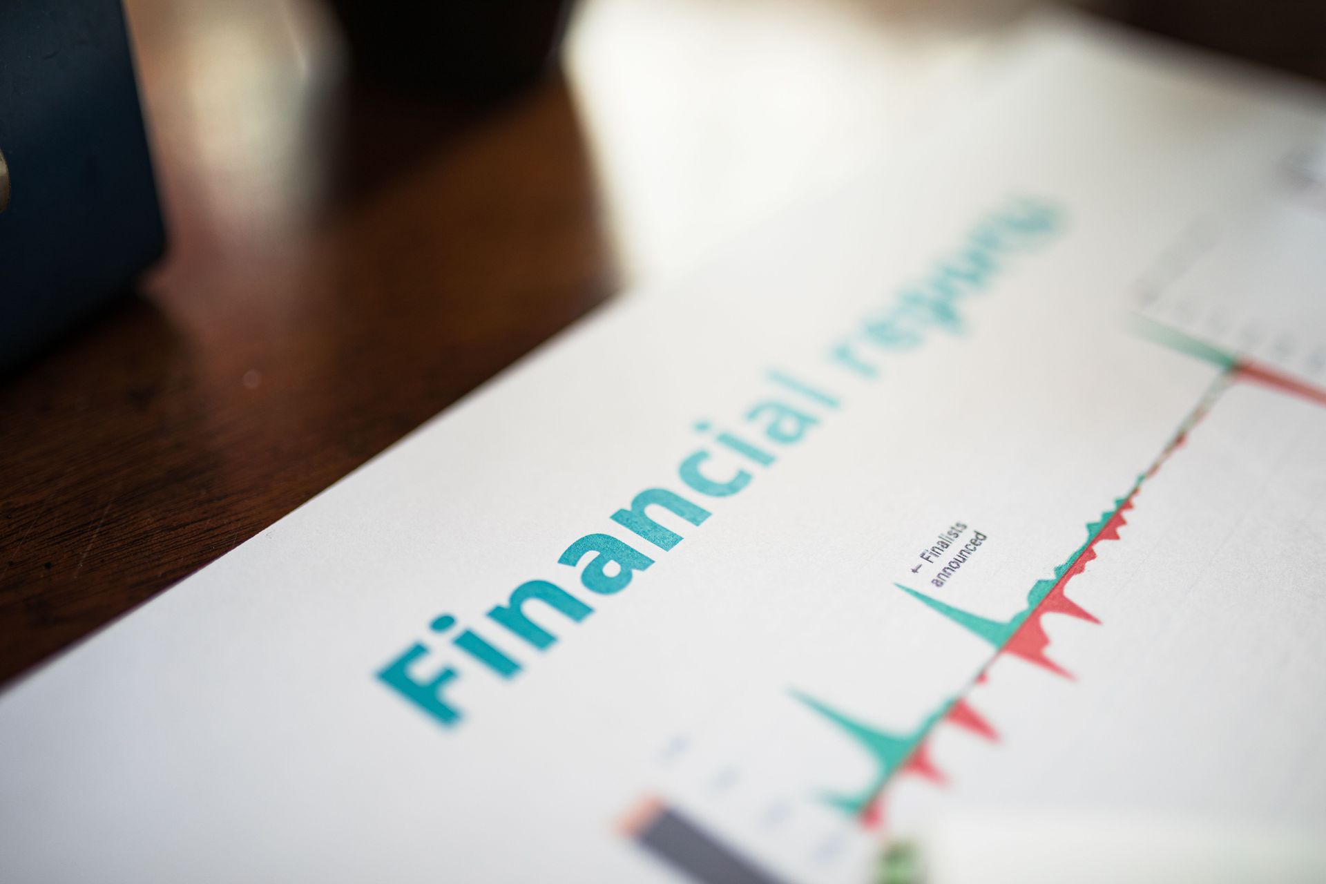 Financial report document with a teal title and a red-green line chart on a desk