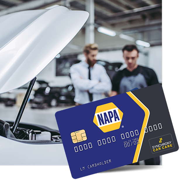 Blue NAPA battery in car engine bay, with two mechanics blurred in the background | Tinley Auto Repair & Towing Inc
