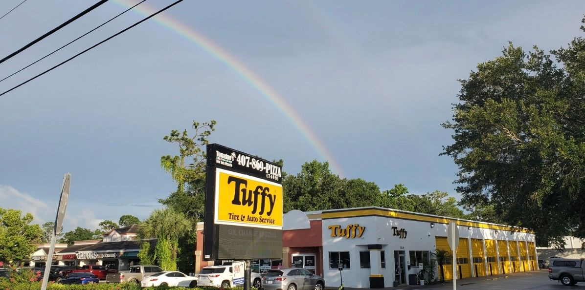 Rainbow arcs over a Tuffy auto service center on a cloudy day.