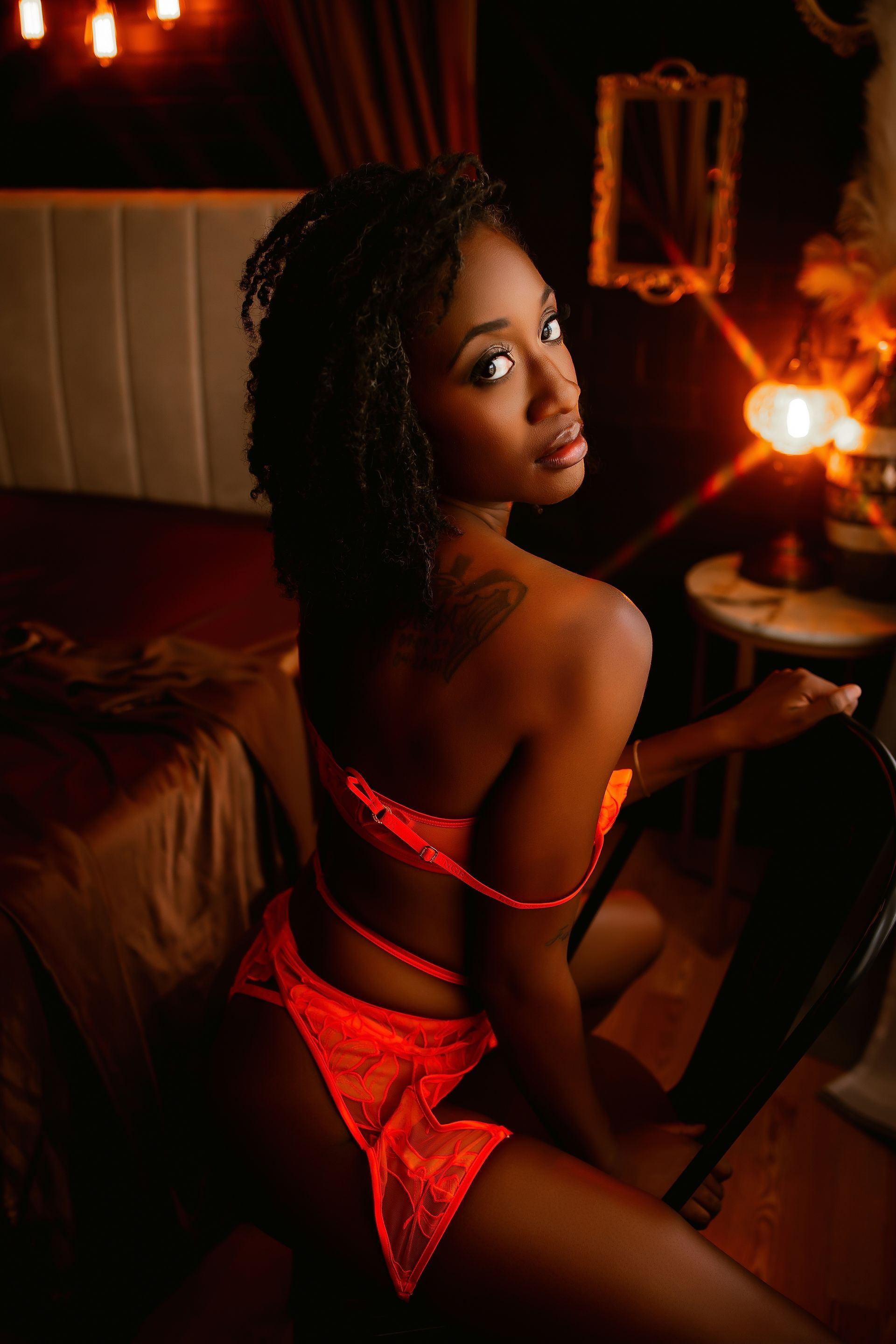 A woman in lingerie is kneeling on a bed in front of a window.