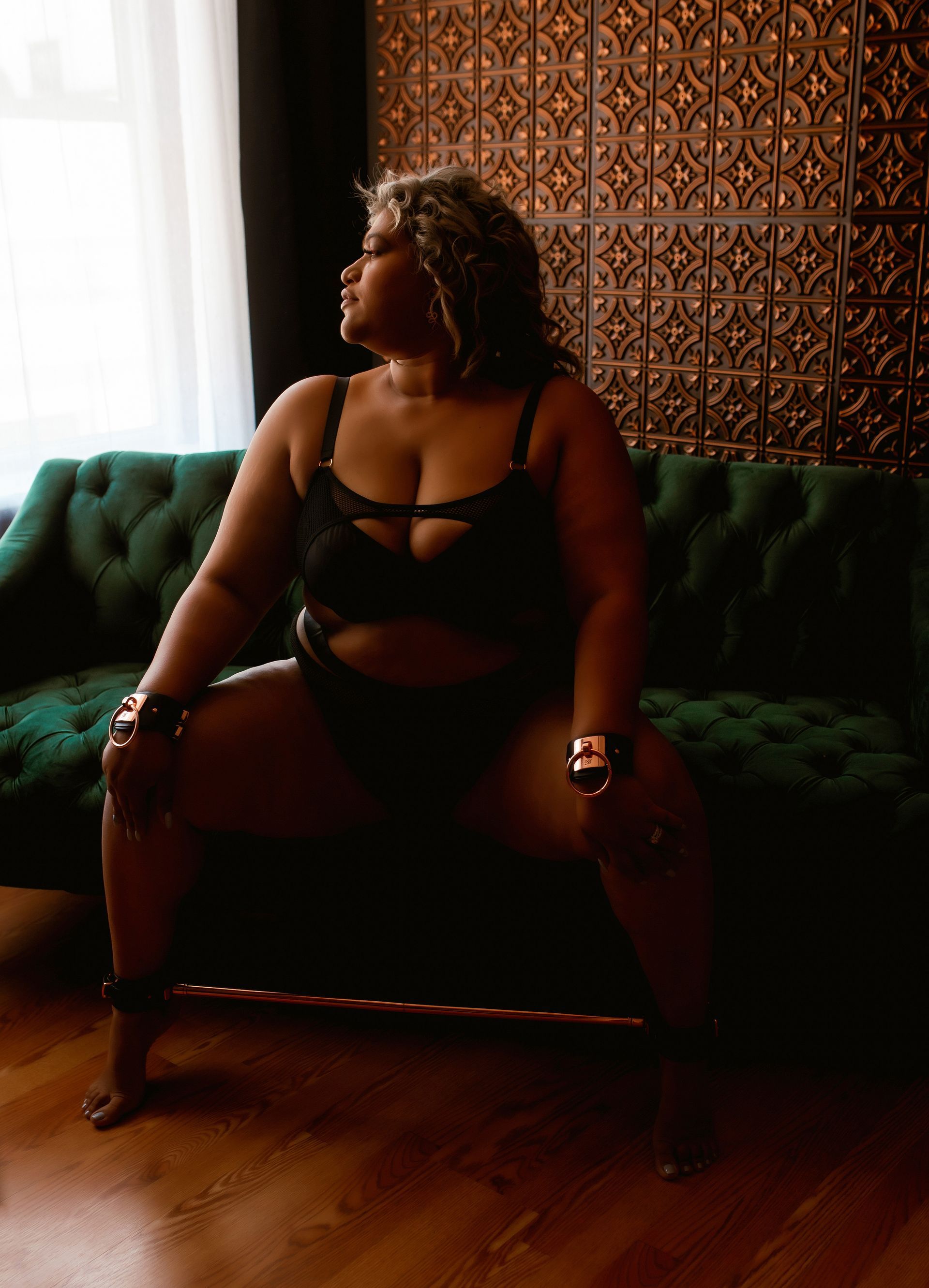 A woman in lingerie is sitting on a green couch.
