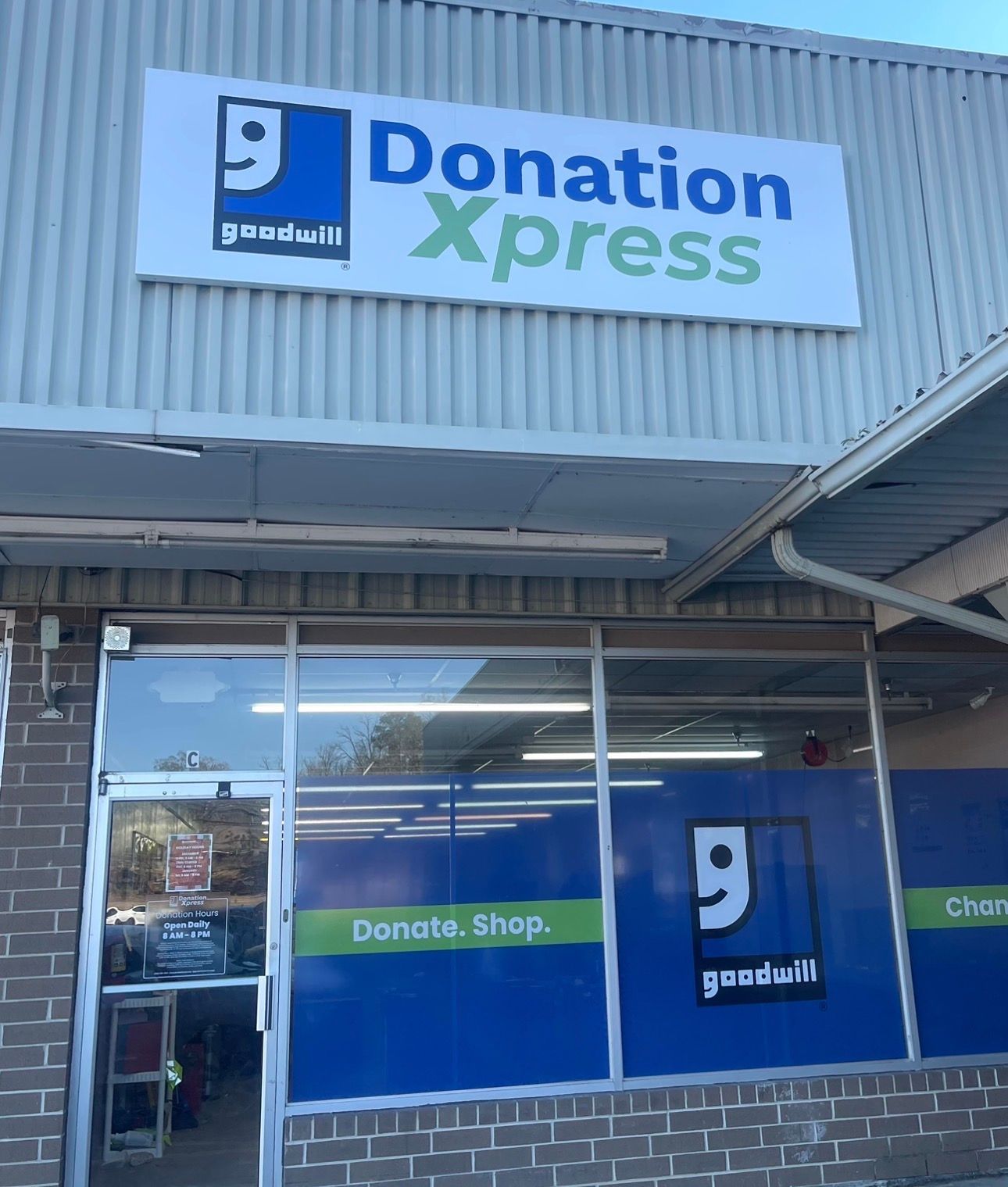 Goodwill Donation Xpress storefront with blue and green signage. A person is inside the door.