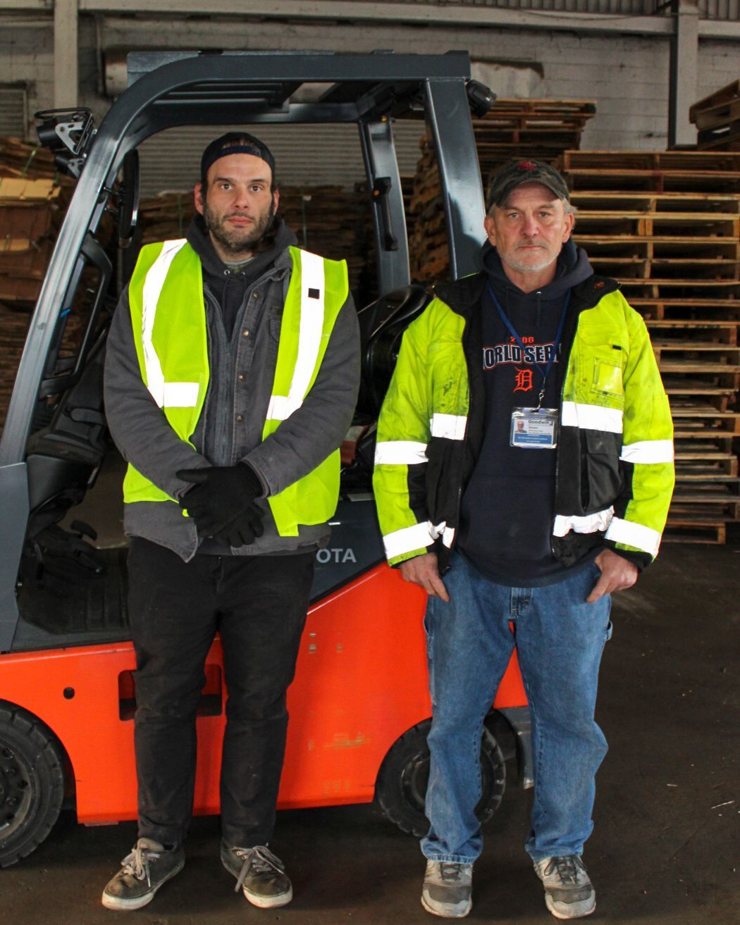 Man in pink shirt sits in blue chair in front of United Way sign.