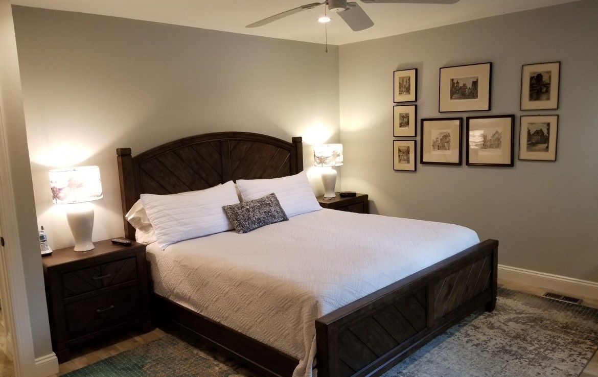 Bedroom with a dark wooden bed, white bedding, nightstands, and framed art on the wall.