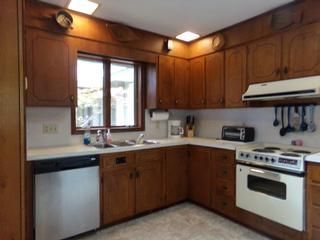 A kitchen with brown cabinets, white appliances, and a window.