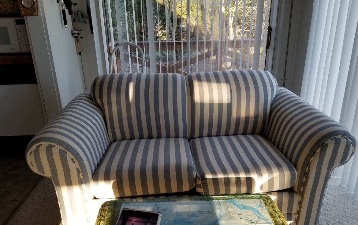 Striped loveseat in a sunlit room, with a small table in front.