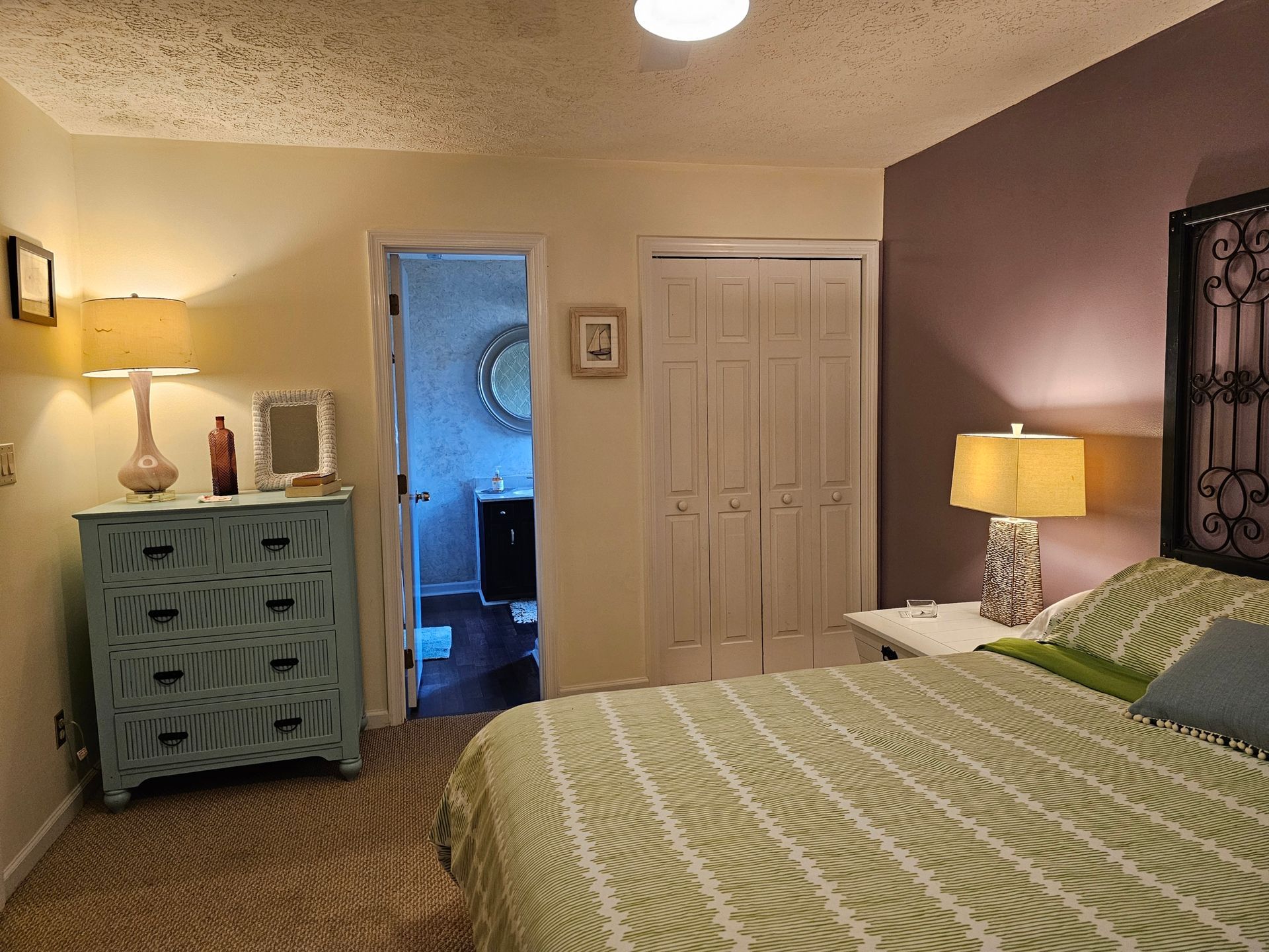 Bedroom with light blue dresser, white closet, and purple accent wall.