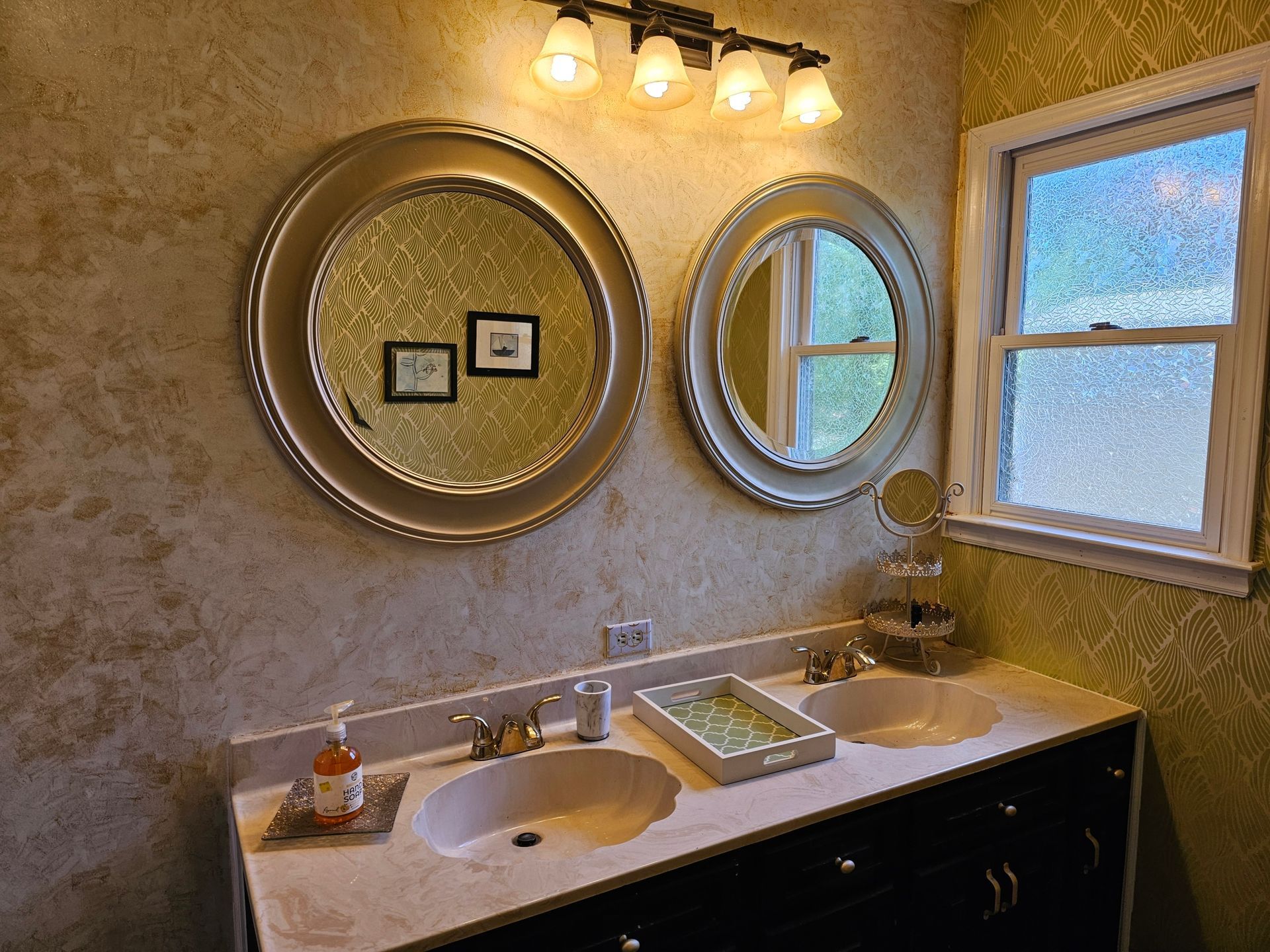 Bathroom with two sinks, two mirrors, a window, and a light fixture above the mirrors.