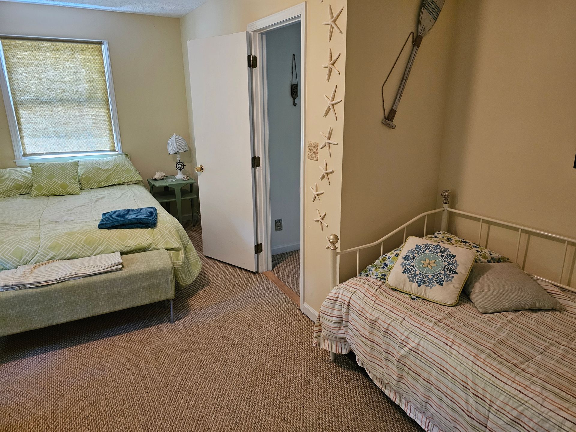 Bedroom with a queen bed and a twin bed, neutral tones with decorative accents.