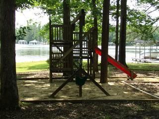 Playground structure with slide and swing set by a lake.