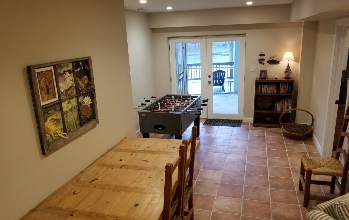 Game room with foosball table, wooden table and chairs, French doors to a deck, and bookshelves.