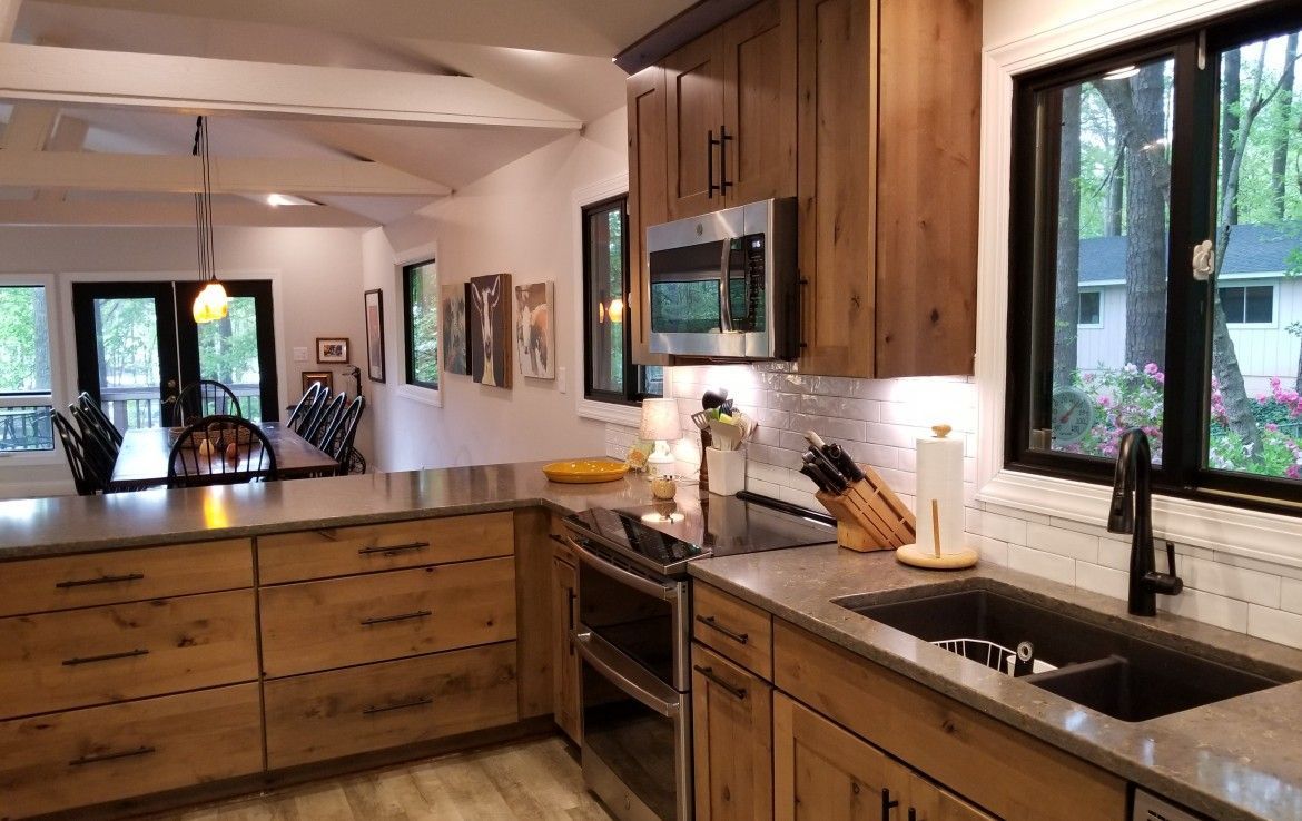A modern kitchen with wood cabinets, stainless steel appliances, and a gray countertop.