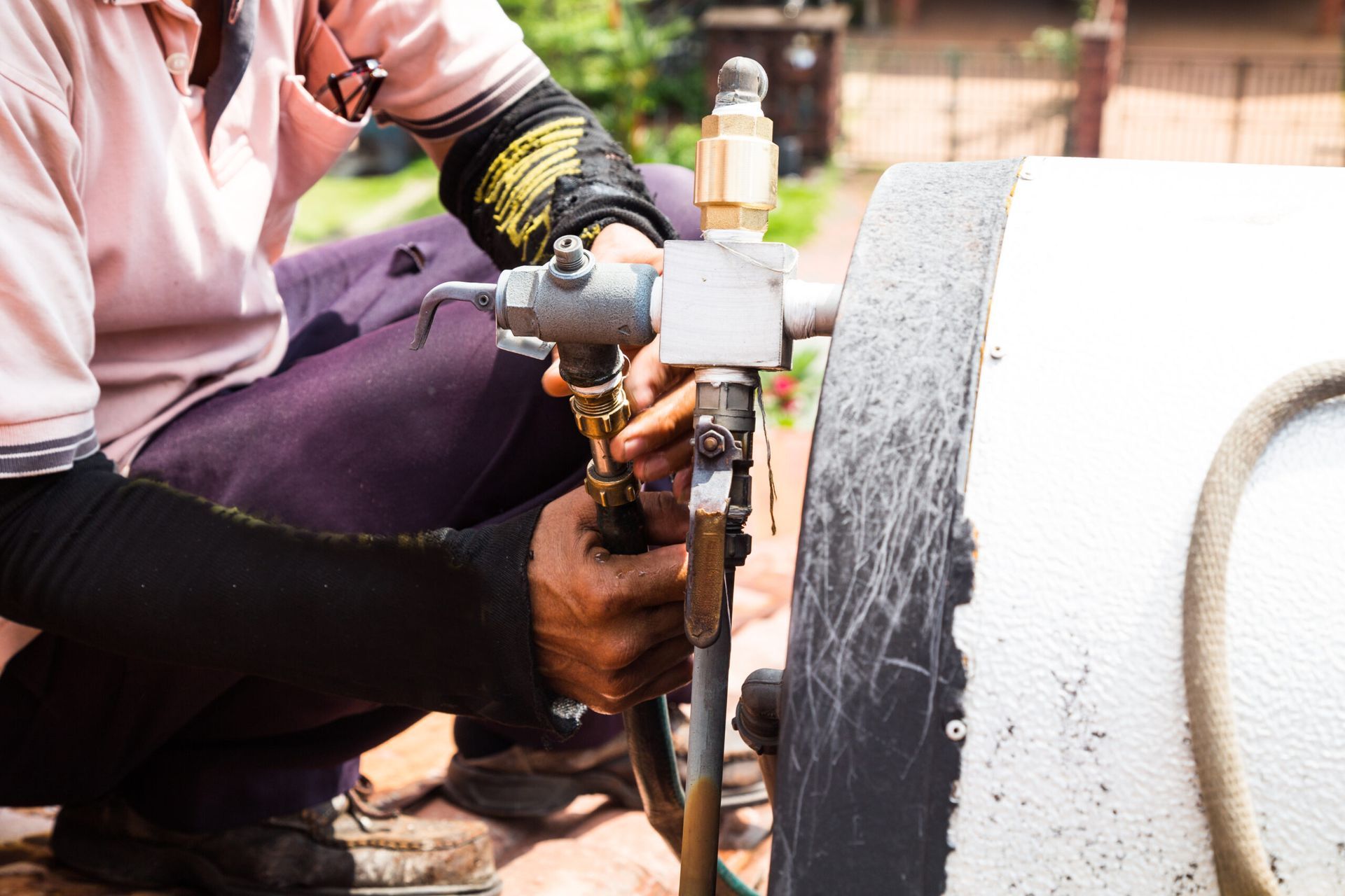 a man is kneeling down and working on a pipe .