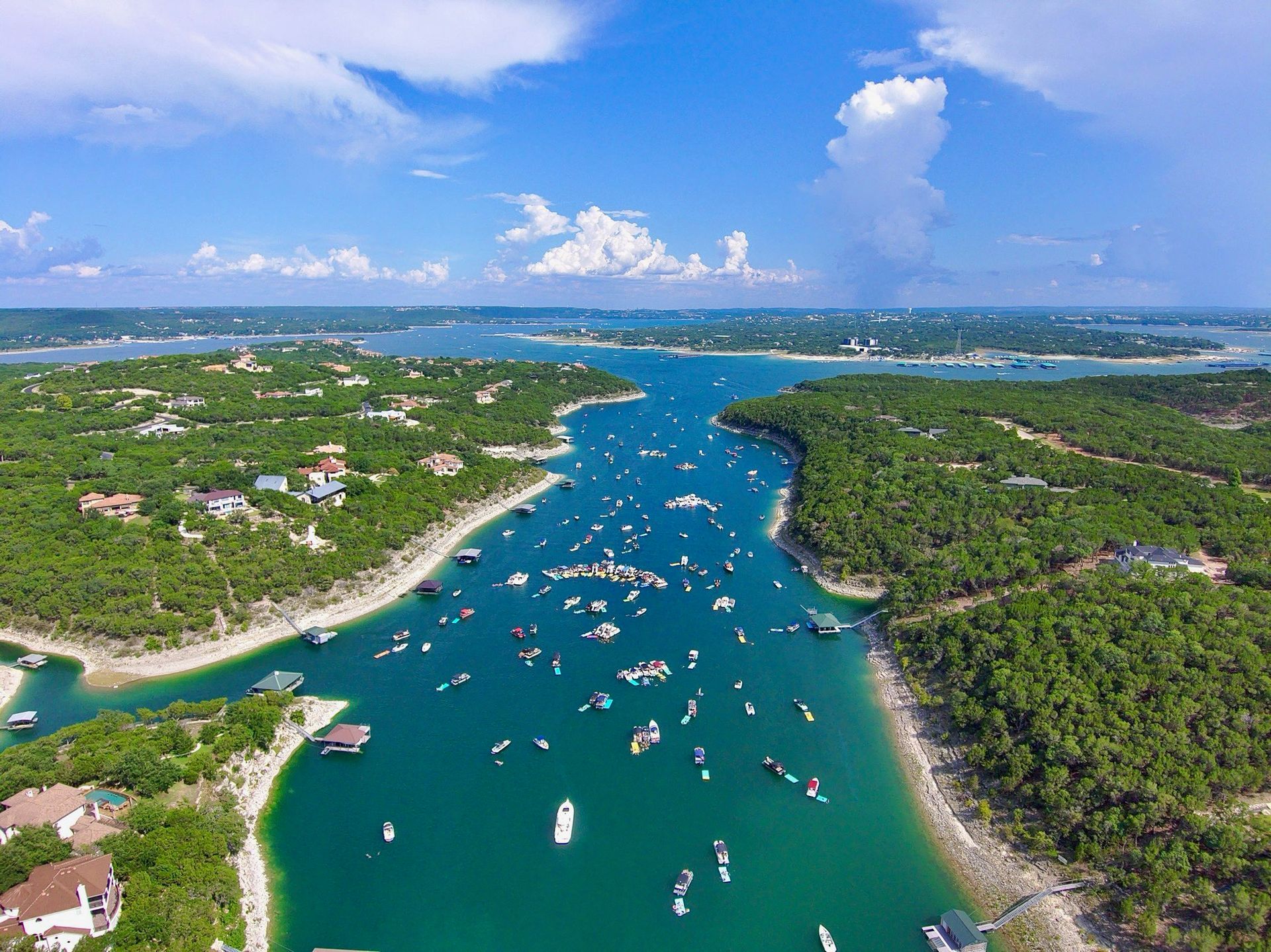 An aerial view of a lake filled with boats on a sunny day.