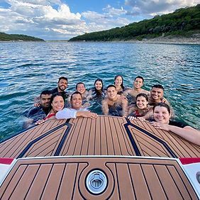 A group of people are sitting on the back of a boat in the water.