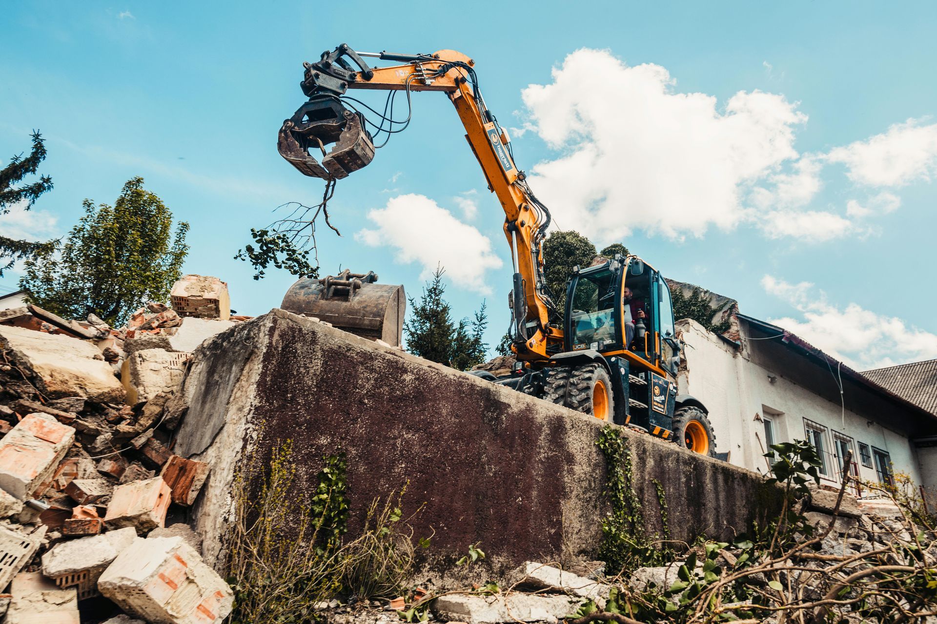 An excavator demolishes a building, blue sky background.