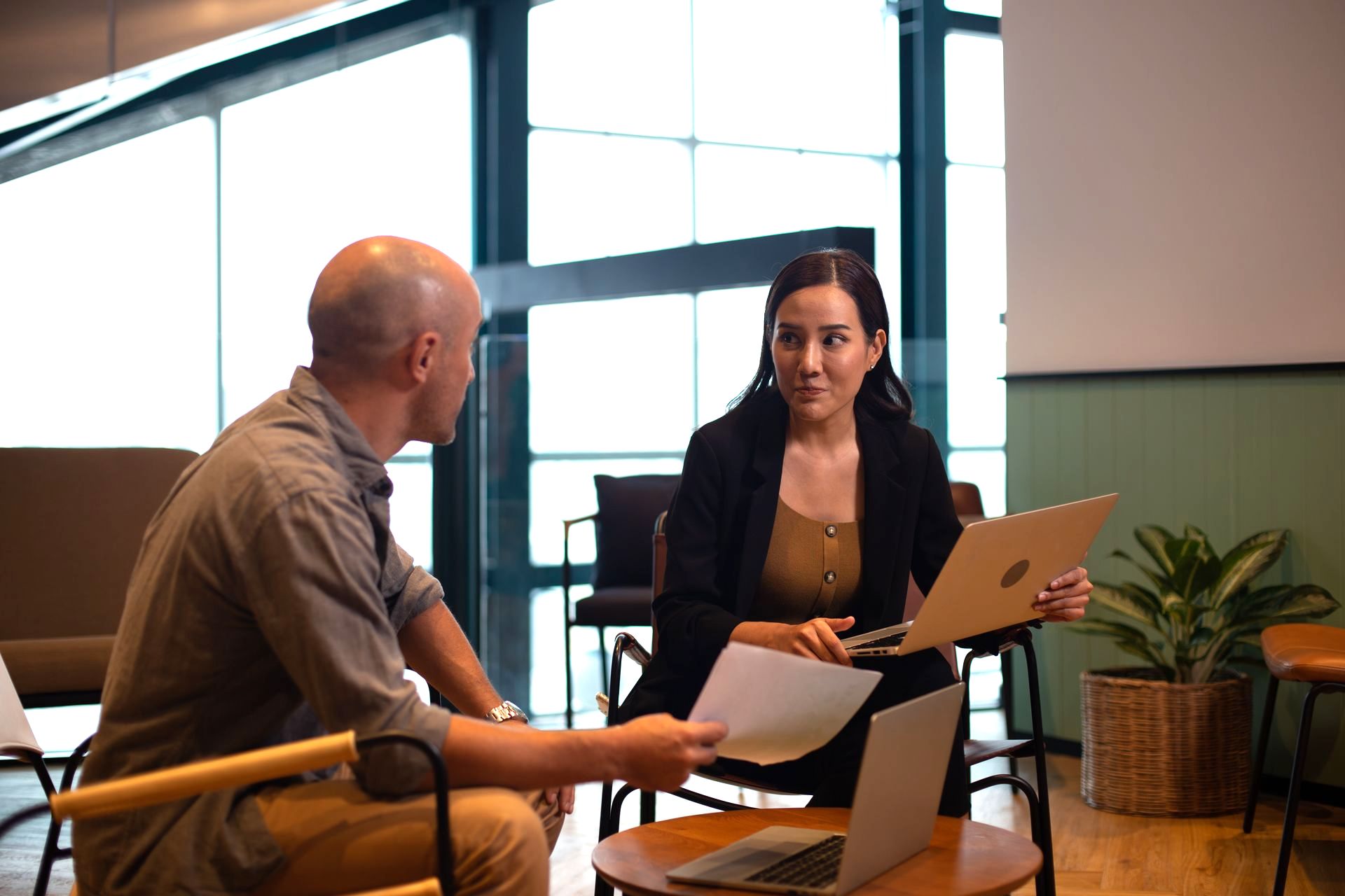 A man and a woman are sitting at a table with a laptop and papers.