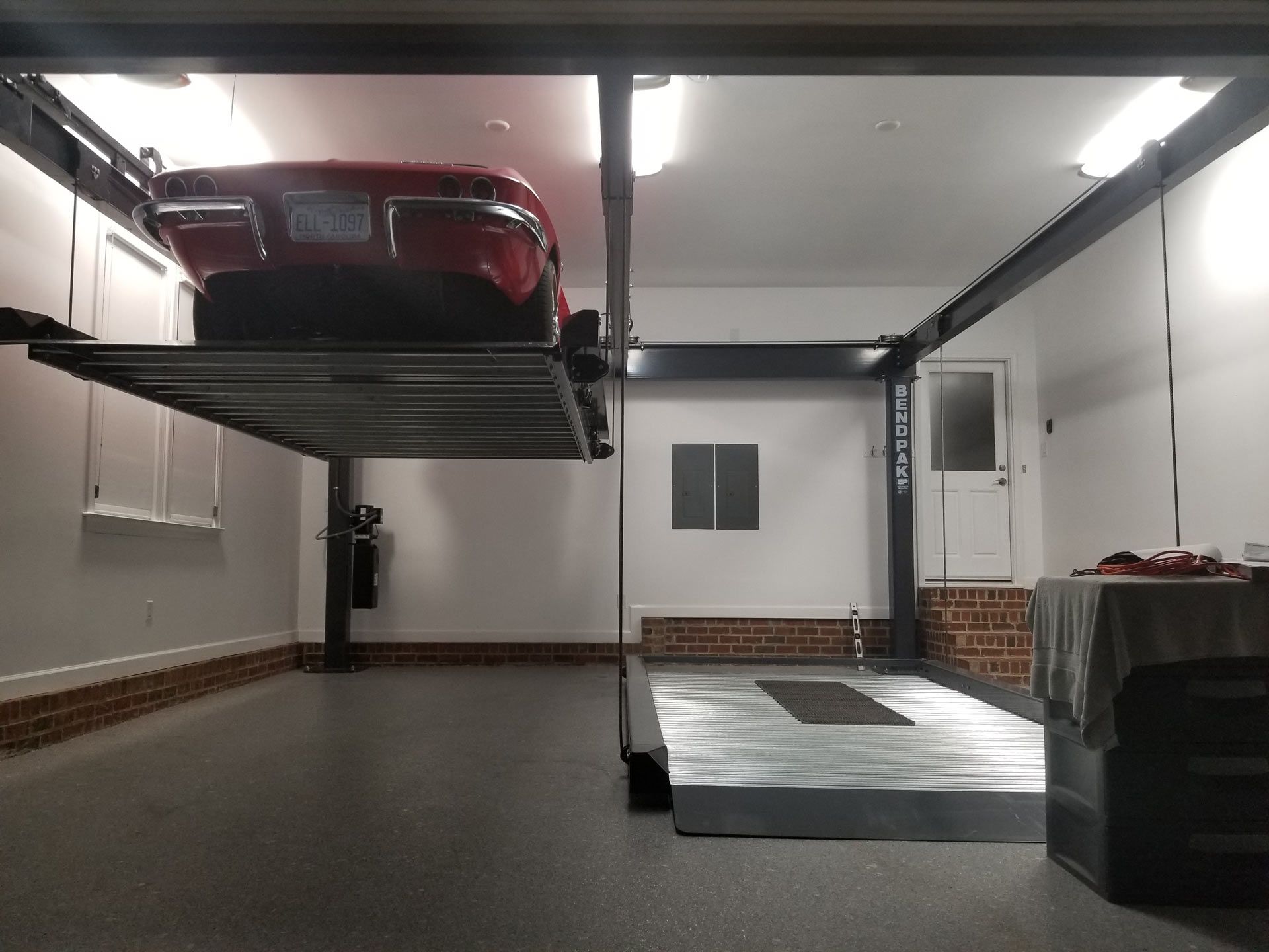 a red car is parked on a lift in a garage