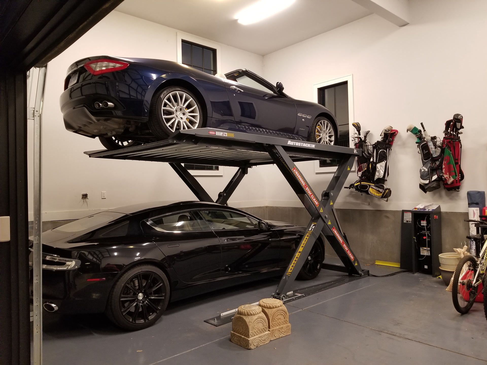 two cars are parked on a lift in a garage