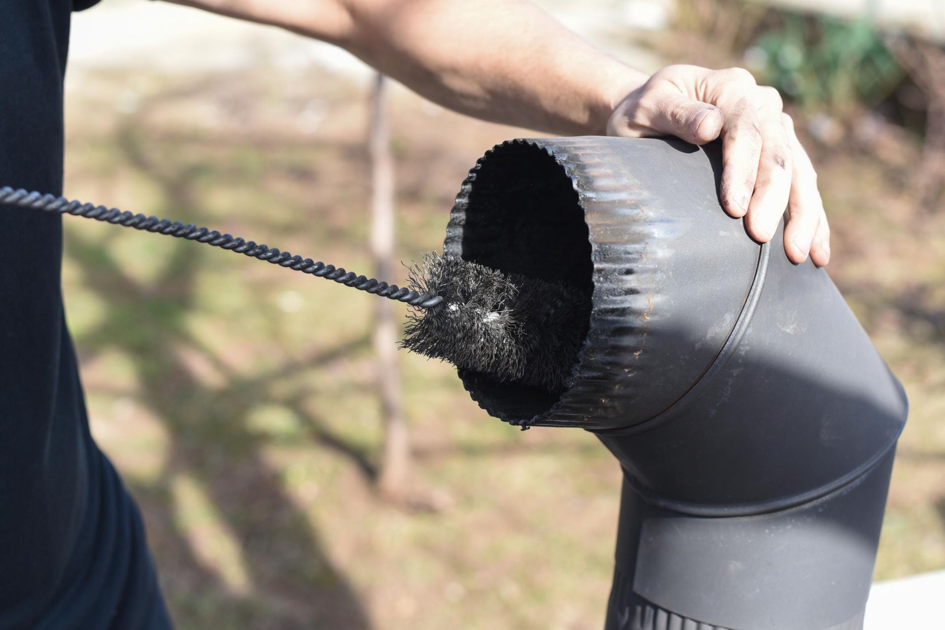 A person is cleaning a chimney with a brush.