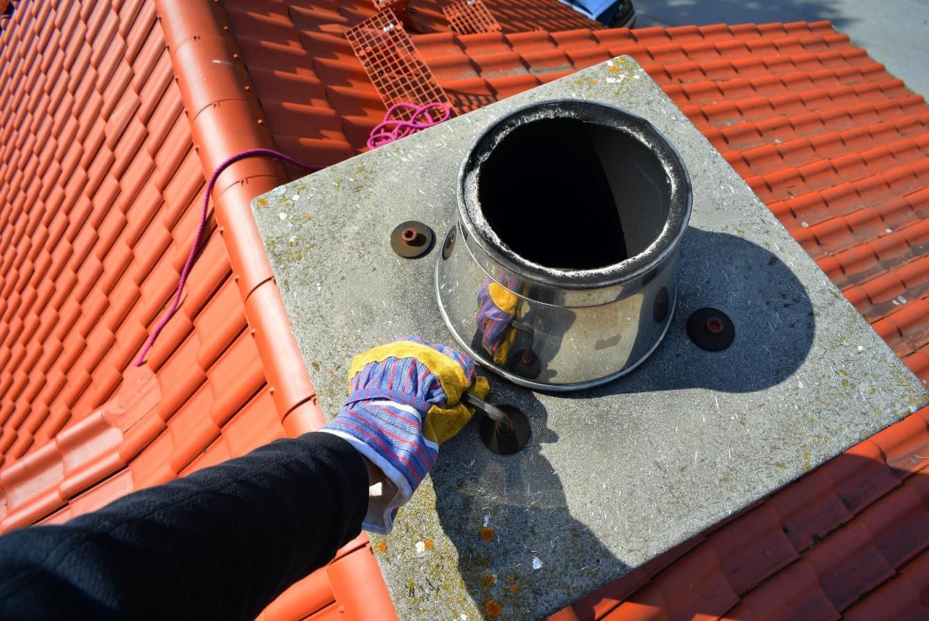 A person is working on a chimney on top of a roof.