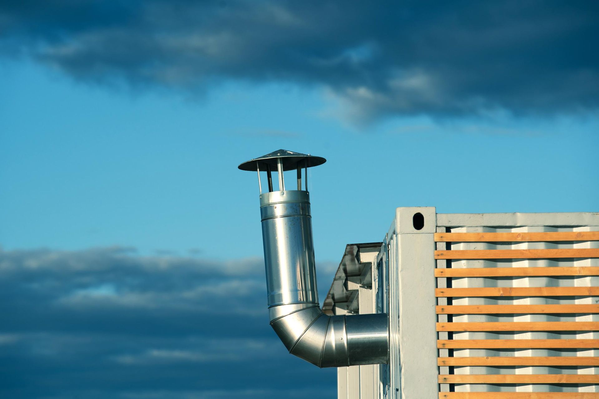 A chimney on the side of a building with a blue sky in the background.