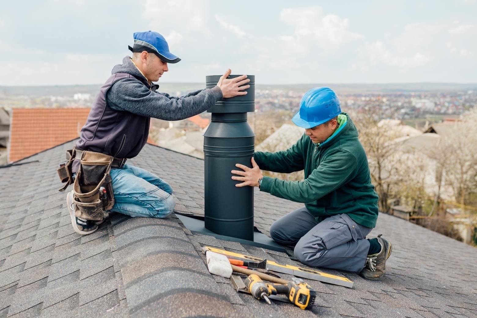 Two men are working on a chimney on a roof.