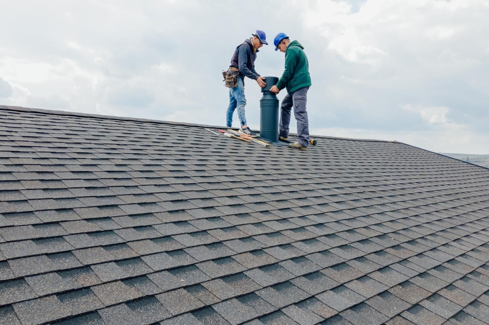 Two men are working on the roof of a house.