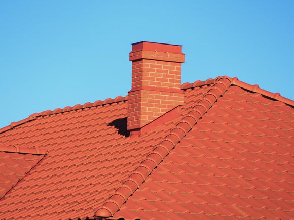 A red tiled roof with a chimney on top of it.
