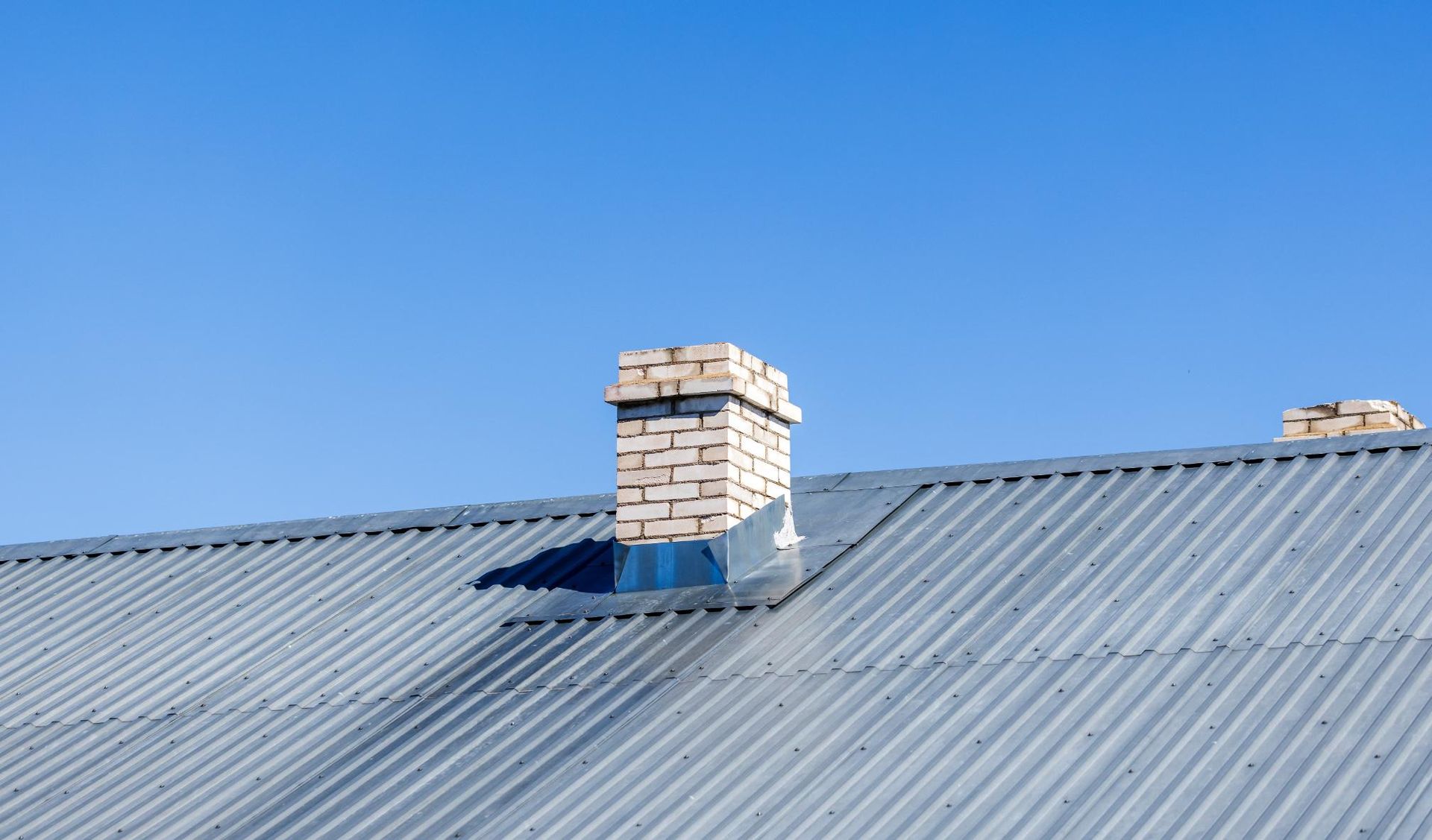There is a chimney on the roof of a house.