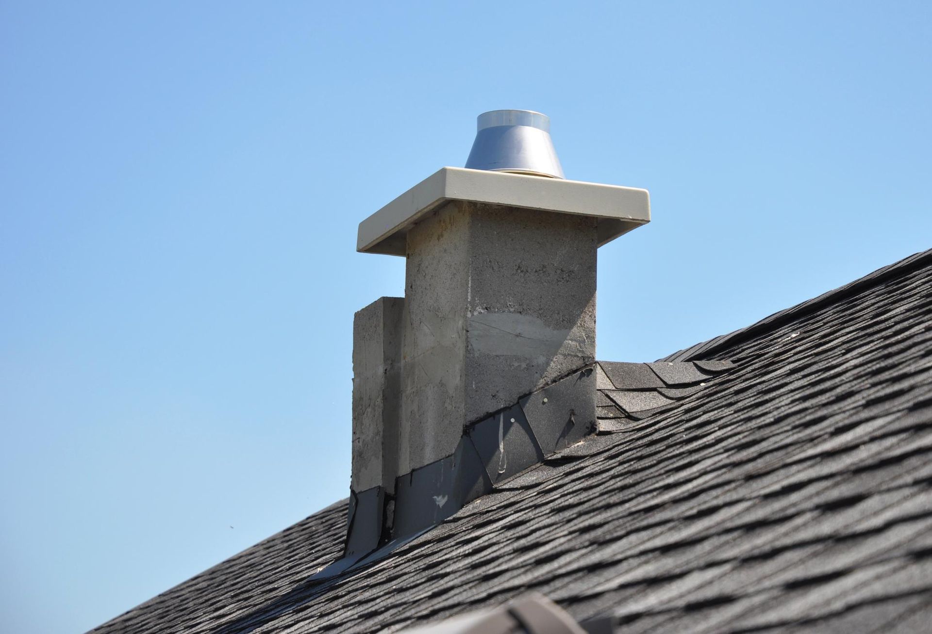 A chimney on top of a roof with a blue sky in the background.