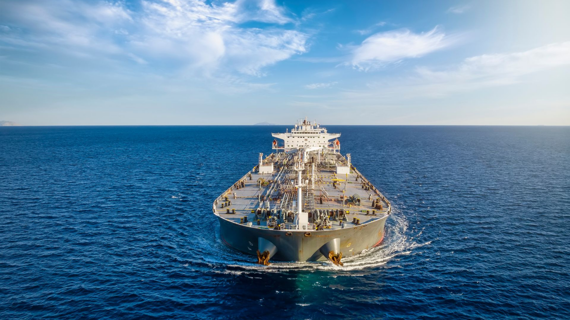 Large oil tanker steaming through a calm, blue ocean under a clear sky.
